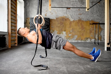 Canvas Print - fitness, sport, bodybuilding and people concept - young man exercising on gymnastic rings in gym