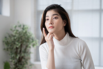 Asian woman is applying cream to her face.