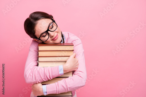 Photo of pretty student lady hugging hands literature pile diligent pupil fond of reading eyes closed dreamer book worm wear shirt pullover specs isolated pastel pink color background