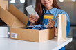 © Farknot Architect - Closeup image of a beautiful young woman using mobile phone and credit card for online shopping with shopping bag and postal parcel box of clothing on the table