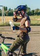 © Alina - Tired sportsman teenager in a safety helmet on a bicycle holds a plastic water bottle in his hands. Drink during sports. Sports stadium. Active lifestyle of people.