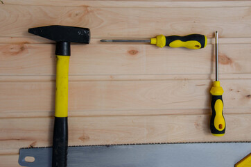 Yellow tools on a wooden background. Hammer saw screwdriver together place for inscription. She drank a hammer.