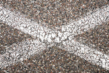 White paint line. X shape. Lines crossing. Grunge asphalt structure texture. Closeup granular noise background. Street grain pattern. Cracked paint stipe. Marked point.