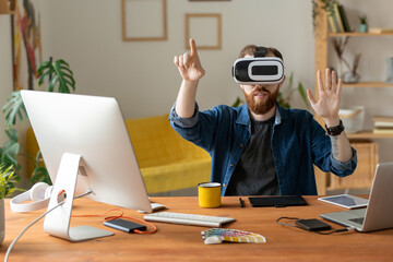 Wall Mural - Young bearded man touching invisible screen while working on virtual design in virtual reality headset