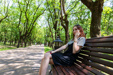 Charming red-haired girl in the Park talking on a mobile phone