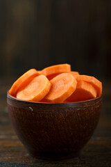 Canvas Print - Sliced carrots in a bowl on a wooden background. Vegetable, ingredient and staple food.