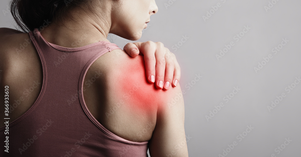 Young strong sporty woman suffering from pain in shoulder in sport wear. Touching the hand. Sports exercising injury. Closeup portrait with highlighted in red and empty space. Back view. The concept - obrazy, fototapety, plakaty 