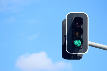 Green traffic lights with a sky background