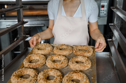 Fotomural Close up baker is holding a tray with fresh bagels at baking manufacturer factory