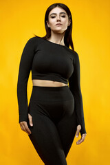 Gorgeous body positive Latin woman in a black suit on a yellow background