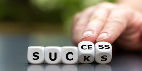 Wall Mural - Hand turns dice and changes the word sucks to success.