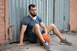 © Vladimir - Man rests on the street near a wall after playing basketball