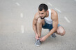 © Vladimir - Sporty man ties the laces on his sneakers before running on the street