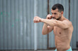 © Vladimir - Athlete conducts a fight with the shadow. A boxer trains punches on the street