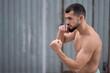 © Vladimir - Athlete conducts a fight with the shadow. A boxer trains punches on the street