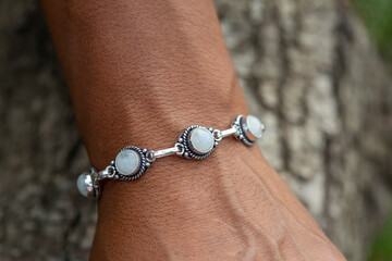 Wall Mural - Outdoor closeup of a hand wrist wearing silver metal bracelet with moon stone gem