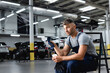 © LIGHTFIELD STUDIOS - tired technician in overalls holding cap and disposable cup while sitting near cars in service station