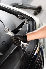 Wall Mural - Cropped view of auto mechanic in latex glove holding wrenches near open hood