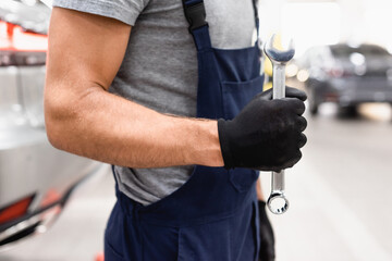 Wall Mural - cropped view of mechanic in latex glove and uniform holding wrench