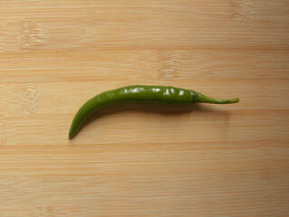 Wall Mural - Green color raw whole Chili pepper on wood background