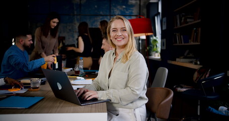 Wall Mural - Zoom in portrait of happy positive young blonde Caucasian business woman smiling at camera working at modern loft office