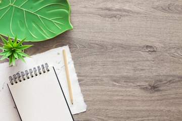 Sticker - Wooden home desk. Copy space. Drawing supplies, an open sketchbook and a ceramic monstera leaf as decoration. View from above.