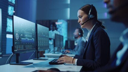Leinwandbilder - Happy Confident Technical Customer Support Specialist Having a Headset Call while Working on a Computer in a Dark Monitoring and Control Room Filled with Colleagues and Display Screens.