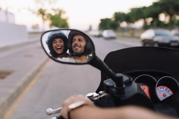 Image of smiling business couple rides on modern motorbike outdoors and looking at the mirror