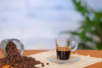 Black coffee in glass cup and coffee beans on the wooden table