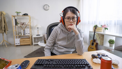 Unhappy teenager girl wearing headphones looks sadly at camera lost online game. negative lazy female homebody in serious emotion after enemy win video computer game on internet in dirty room.