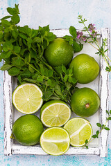 Wall Mural - Lime and mint on light wooden tray, blue concrete background. Summer concept. Top view.