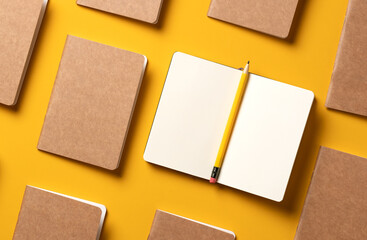 content marketing concept,.top view of hand writing on open notebook and yellow pencil align with kraft paper book in pattern on yellow table background.mockup for advertise content online