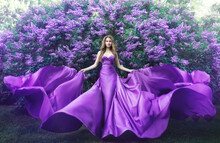 Fashion Model In Lilac Flowers, Young Woman In Beautiful Long Dress Waving On Wind, Outdoor Beauty Portrait In Blooming Garden