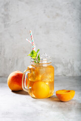 Wall Mural - Peach ice tea on concrete gray background with mint and ice