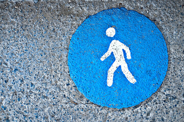 Road for pedestrians, blue round sign painted with stencil on a pavement.