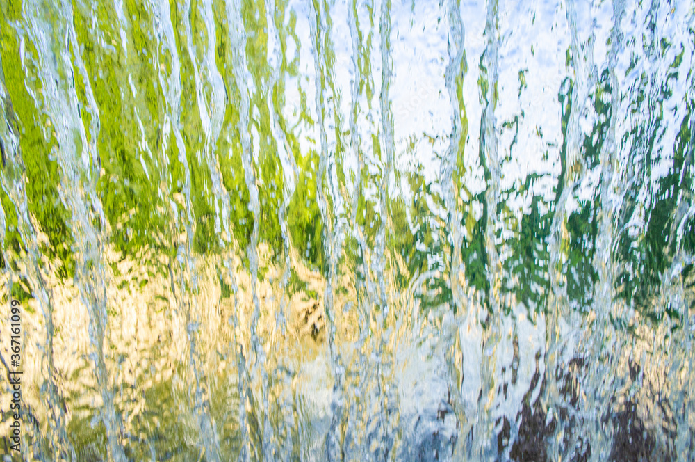 The texture of a transparent water wall from jets of water flows down. Close-up view