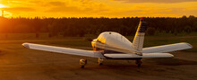 Rear View Of A Parked Small Plane On A Sunset Background. Silhouette Of A Private Airplane Landed At Dusk.
