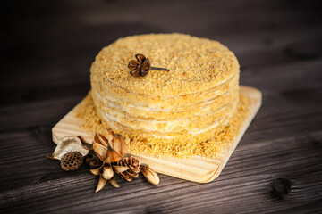 Wall Mural - homemade honey cake decorated with golden wooden flowers on dark background