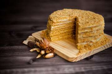 Wall Mural - homemade honey cake decorated with golden wooden flowers on dark background