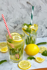 Refreshing drinks for summer, cold sweet and sour lemonade juice in the glasses with sliced fresh lemons. Refreshing summer drink. Traditional lemonade with lemon, mint and ice. Selective focus