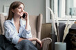 Young cheerful woman talking on mobile phone at home