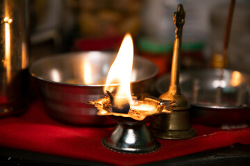 Dia oil lamp burning by Cotton Wick during Teej Festival of India in home for married women with the brass bell and bowl kept for prasad and other worshipping Ganpati Ganesh Pooja