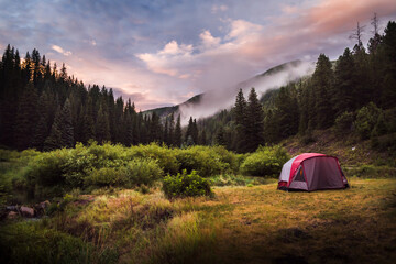 a tent set up in the mountains during sunset.