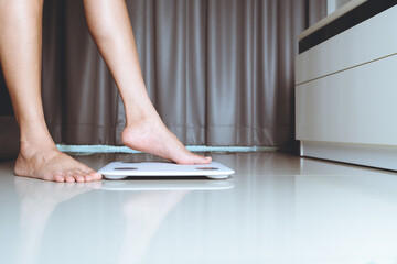 Female leg is stepping on white scales at home