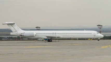 Wall Mural - Side view of airplane. White commercial passenger jet airliner on airport apron. Cloudy sky background. Modern technology in fast transportation, business travel aviation, tourism charter flights.