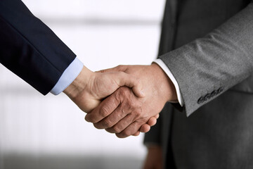 Business people in office suits standing and shaking hands, close-up. Business communication concept. Handshake and marketing