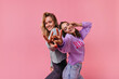 Fascinating emotional girls laughing to camera and having fun. Studio portrait of joyful friends isolated on bright background.