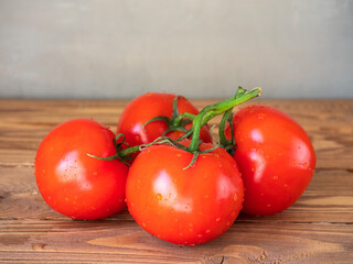 A branch of red tomatoes lies on a brown wooden table