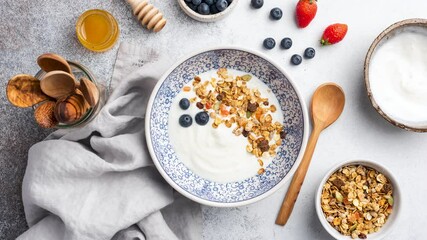 Wall Mural - Stop motion animation of yogurt with granola and berries. Eating greek yogurt with crunchy oat honey granola, blueberries, strawberries and pomegranate seeds. Healthy food concept