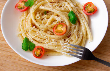 Spaghetti with cherry tomatoes and cheese on a wood board close-up